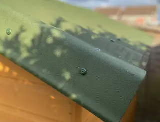 Pièce de rive verte vissée le long du pignon d'un abri, recouvrant le bord des plaques