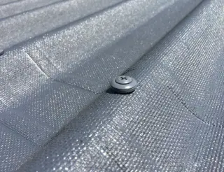 Gros plan d'une vis à rondelle d'étanchéité posée en sommet d'onde sur une plaque bitumée gris anthracite