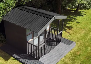 Abri de jardin en bois couvert de plaques ONDULINE 9S noires, avec un auvent sur terrasse
