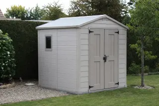 Abri de jardin en résine composite gris clair à double porte, dans un jardin
