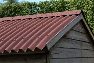 Toiture d'abri en plaques bitumées ondulées ONDULINE rouge, fixations à rondelle d'étanchéité intégrée en sommet d'onde, sur une structure en bois