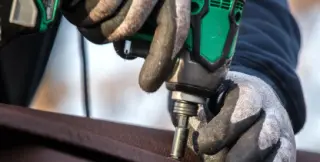 Vissage en sommet d'onde d'une plaque bitumée ondulée ONDULINE EASYFIX® sur la charpente d'un abri de jardin, avec une vis à rondelle d'étanchéité intégrée