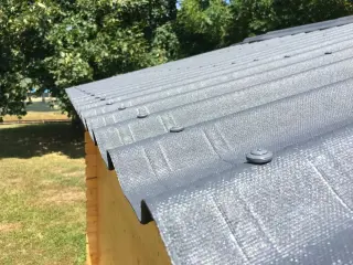 Plaques bitumées ONDULINE EASYFIX® anthracite posées avec leurs recouvrements sur un abri de jardin, fixations en sommet d'onde