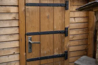 Porte de cabanon en bois massif avec pentures longues, gonds anti-dégondage et serrure de sûreté encastrée, montée sur cadre renforcé